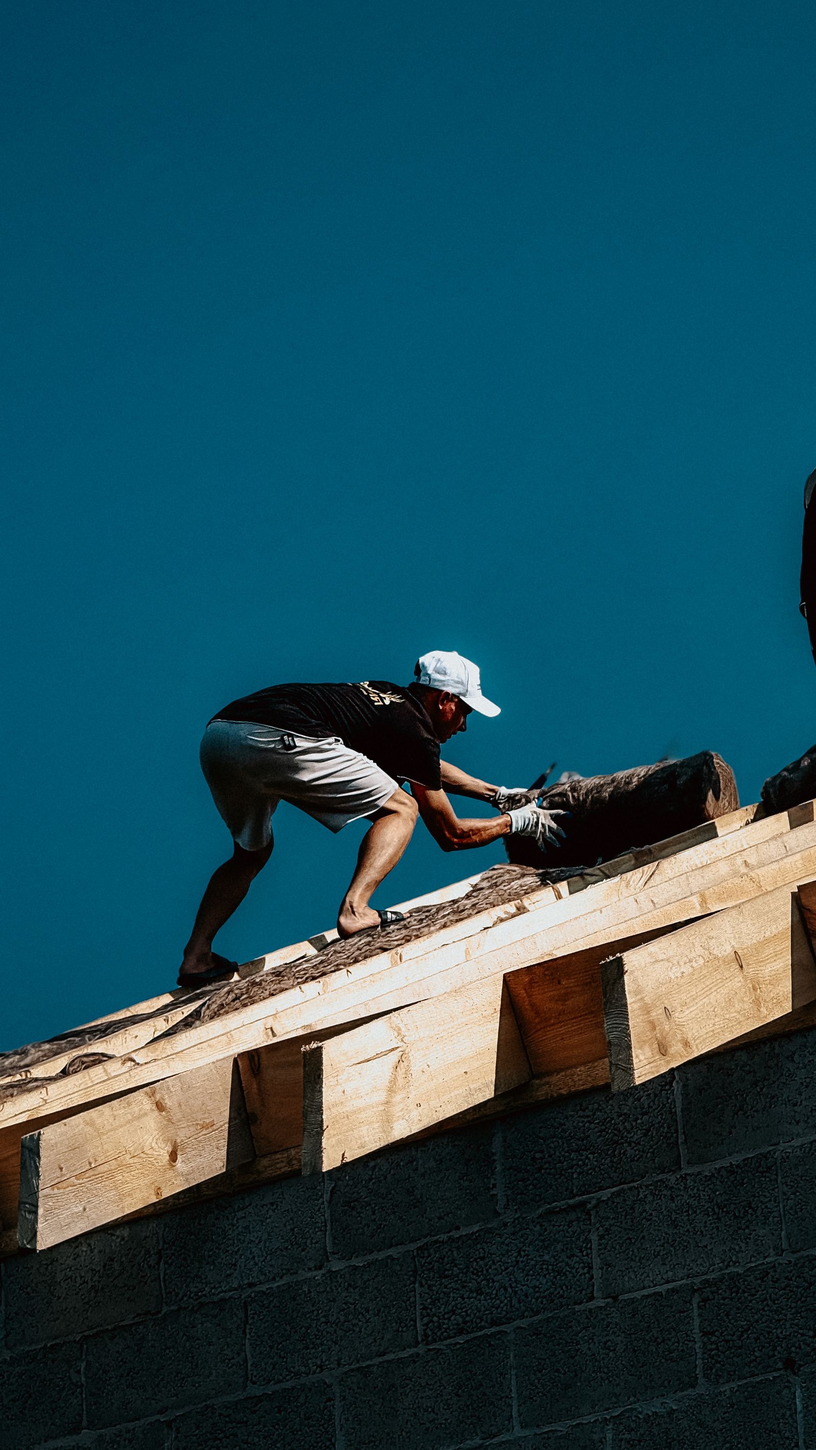 A roofer working along a roof ridge