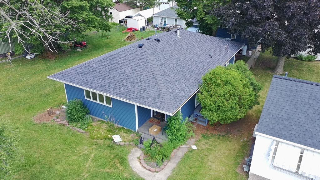 Completed Eagle Star roof in grey shingles on a blue-sided home